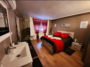 1 dormitorio con cama con almohadas rojas y lavamanos en Relais des Vosges, en Husseren-Wesserling