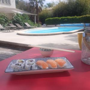 una bandeja de sushi en una mesa junto a una piscina en Studio avec piscine, en Corbère
