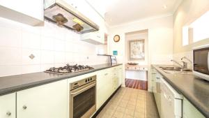 a kitchen with white cabinets and a stove top oven at Beachside Beauty With Pool in Woorim +7 photos