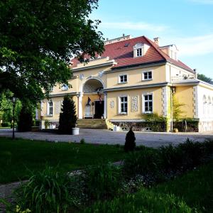 Pałac Bugaj في Raszków: منزل اصفر كبير بسقف احمر