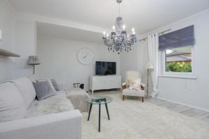 Sala de estar blanca con sofá y lámpara de araña en Kooli Apartment, en Pärnu