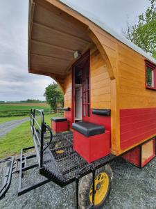 une petite maison sur roues avec une terrasse couverte dans l'établissement Véritable roulotte hippomobile "LA BAILLEUL", à Mentheville