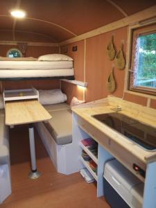 - une petite cuisine avec un bureau et un lit dans une caravane dans l'établissement Véritable roulotte hippomobile "LA BAILLEUL", à Mentheville