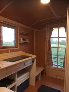 - une petite cuisine avec un comptoir et 2 fenêtres dans l'établissement Véritable roulotte hippomobile "LA BAILLEUL", à Mentheville