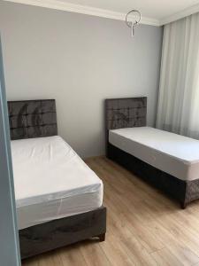 two beds in a room with white walls and wooden floors at Aydın Apart in Bostancı