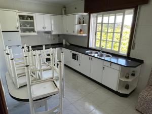 a kitchen with white cabinets and a sink and chairs at Apartamentos Rial in Sanxenxo