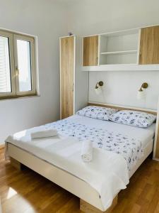 ein Schlafzimmer mit einem großen Bett mit weißer Bettwäsche in der Unterkunft Apartments Ivankovic in Rogoznica