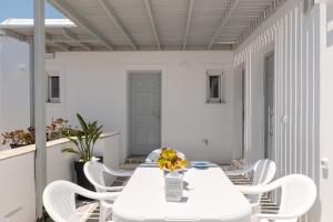 a white table with white chairs and a vase of flowers at ALTHEA PAROS in Naousa