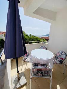 einen Tisch, Stühle und einen Regenschirm auf dem Balkon in der Unterkunft Apartments Ivankovic in Rogoznica