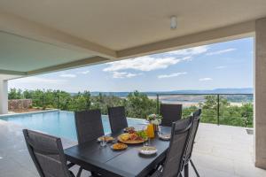 a dining room with a table and chairs and a pool at Villa El Viento in Šmrika