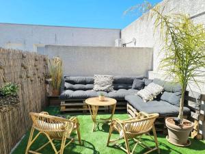 a patio with a couch and two chairs and a table at AppartCosy Emplacement Idéal avec Terrasse & Parking Privé in Nîmes