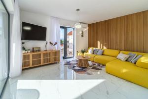 a living room with a yellow couch and a tv at Villa Dono in Sutivan