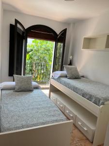 a bedroom with two beds and a large window at La Bicicleta, Duplex en Vélez Benaudalla in Vélez de Benaudalla
