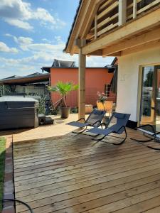 a deck with two chairs and a hot tub at Landliebe, Luxus-Ferienhaus, 3 Schlafzimmer mit Sauna und Outdoor Whirlpool in Geierswalde