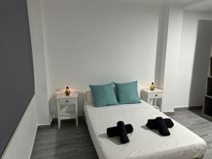 een bed met twee zwarte pantoffels erop in een kamer bij Estadio playa in Almería