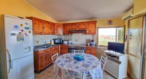a kitchen with a table and a white refrigerator at Blue Horizon Calabria - Seaside Apartment 120m to the Beach - Air conditioning - Wi-Fi - View - Free Parking in Santa Caterina Dello Ionio Marina