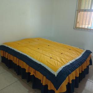 ein Bett mit einer gelben und blauen Decke drauf in der Unterkunft Lugar perfeito para você e sua família in Rio Grande