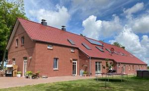 un grand bâtiment en briques avec des panneaux solaires dans l'établissement Landhaus "Alte Welt" Nordseeküste, à Osteel