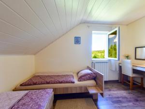 Cette chambre comprend deux lits, un bureau et une fenêtre. dans l'établissement Apartments Marija, à Rakovica