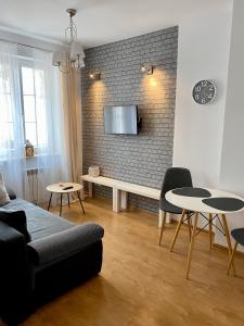 een woonkamer met een bank en een tv aan een bakstenen muur bij Apartament Nadjeziorna Villa Park in Ełk