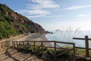 a wooden fence next to a beach next to the water at Cav la Ginestra vistamare Elba in Rio nellʼElba