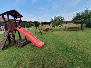 a playground with a red slide in a park at Corvina Hotel-Restaurant in Mosonmagyaróvár