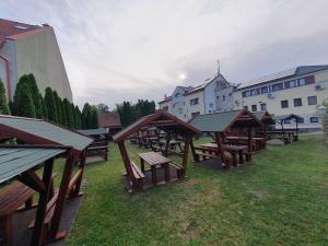 a group of picnic tables in a field with buildings at Corvina Hotel-Restaurant in Mosonmagyaróvár