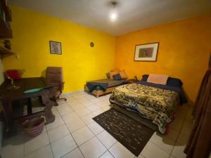 um quarto com paredes amarelas, uma cama e uma secretária em Calli Tonanzin em Tepoztlán