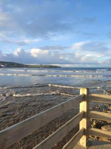 una valla de madera en una playa con el océano en Nordés Apartamentos Turísticos - Bañugues, en Bañugues