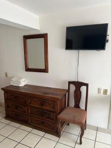een kamer met een dressoir, een stoel en een spiegel bij HOTEL JERUSALEM in San Juan de los Lagos