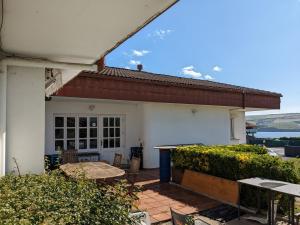 Dieses weiße Haus verfügt über eine Terrasse mit einem Tisch und Stühlen. in der Unterkunft Nordés Apartamentos Turísticos - Bañugues in Bañugues