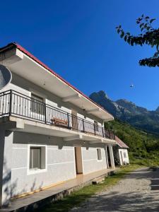 Lazer Cardaku guest house في فالبني: مبنى مع شرفة مع جبال في الخلفية
