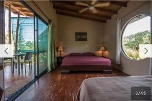 a bedroom with a bed and a large window at Eden Tica Lodge in Uvita