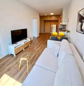 een woonkamer met een witte bank en een flatscreen-tv bij Mokotów Prime Apartment in Warschau