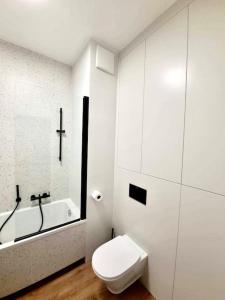 een witte badkamer met een toilet en een bad bij Mokotów Prime Apartment in Warschau
