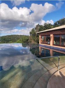 uma casa com uma piscina com vista para a água em Bangalô Villas do Pratagy 1 Dormitório e Varanda em Maceió