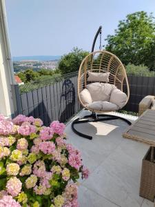 een rieten stoel op een balkon met bloemen bij Mediterranea private pool apartment in Solin