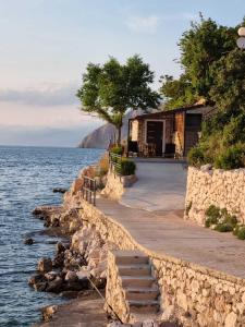 a building next to the water with stairs next to it at Apartman Ulrich in Lukovo