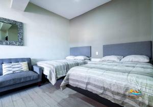 a bedroom with two beds and a chair and a mirror at San Felipe rental - One block to San Felipe Malecon in San Felipe