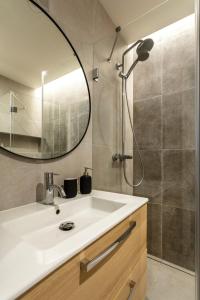 een badkamer met een wastafel en een douche met een spiegel bij Luxury Residence Kmochova in Praag