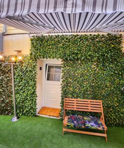 eine Holzbank vor einer grünen Wand mit einer Tür in der Unterkunft Jungle House avec Jacuzzi à 10 min de Disneyland -Taille Chambre- in Condé-Sainte-Libiaire
