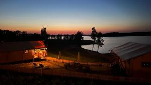 un fienile con un tramonto sullo sfondo di un lago di Wioska Wakacyjna Glamila a Sterławki Wielkie