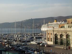 a parking lot with cars parked in front of a harbor at Piazza Venezia Le Camere in Trieste