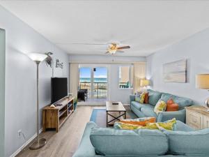 een woonkamer met een blauwe bank en een televisie bij Holiday Surf and Racquet Unit 307 in Destin