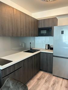 a kitchen with wooden cabinets and a white refrigerator at Villa Bauhaus Dream Deluxe in Siófok