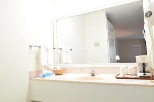 a bathroom with a sink and a large mirror at Hilltop Inn & Suites - North Stonington in North Stonington