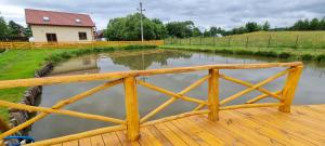 Przytulisko Leszczewek في Leszczewek: جسر خشبي فوق نهر مع منزل