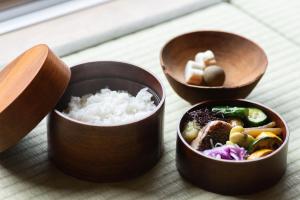 こもる五所川原 في Goshogawara: ثلاثة أواني خشبية من الطعام مع الأرز على طاولة