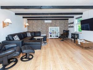 a living room with black leather furniture and a fireplace at Holiday home Løgstør IX in Løgstør