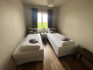 two beds in a small room with a window at Álftártunga Farm Guesthouse in Borgarnes
